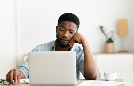 a man who is in front of a laptop has a difficulty concentrating at work because of anxiety